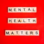 Scrabble tiles on a vibrant red background spelling out "Mental Health Matters," representing the importance of psychological well-being and mental health awareness.
