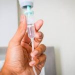 Hand holding a medical IV drip chamber during a fast clinical intravenous hydration therapy session