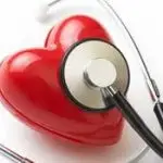 سماعة طبية موضوعة على مجسم قلب أحمر لامع ترمز لتشخيص ومتابعة أمراض القلب والأوعية الدموية