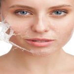 Close-up of a woman peeling a thin skin mask layer from her cheek during a cosmetic cold peeling treatment