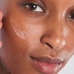 Close-up of a woman applying a hydrating cream to her cheek for a plump skin effect
